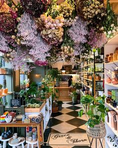 a flower shop filled with lots of different types of flowers hanging from the ceiling and potted plants