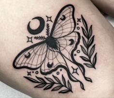 a black and white butterfly tattoo on the thigh with an occupant design