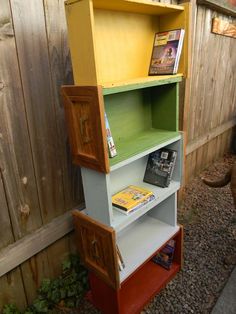 a book shelf with books and magazines on it in front of a fenced area