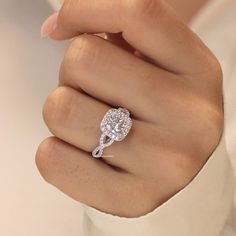 a woman's hand with a diamond ring on top of her finger, holding the engagement ring