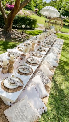 a long table with plates and napkins on it in the middle of a park