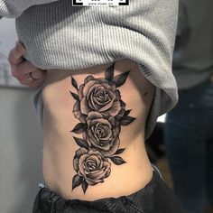 a woman's stomach with three roses tattooed on the side and one flower in the middle