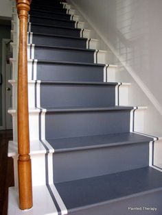 blue carpeted stairs leading up to the second floor with white trim and wood handrails