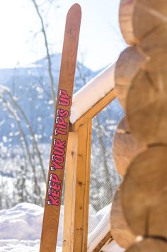 a pair of skis sitting on top of a wooden stand in the snow next to trees