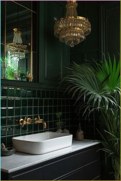 a white sink sitting under a golden chandelier in a bathroom next to a potted plant