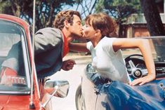 a man and woman kissing in front of a car