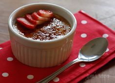 a bowl of pudding with strawberries in it on a red and white polka dot napkin