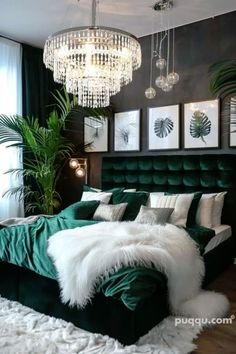 a bedroom with green velvet bedding, chandelier and pictures on the wall