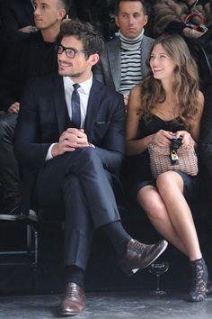 a man and woman sitting next to each other at a fashion show in front of a crowd