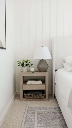 a bedroom with a bed, nightstand and pictures on the wall above it in white paint