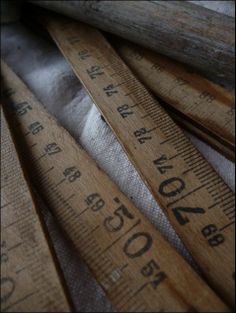 several wooden rulers are stacked on top of each other, with one measuring tape in the middle