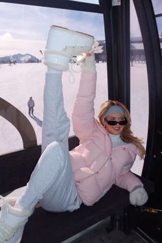 a woman in pink jacket and white pants on ski lift