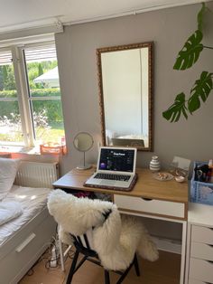 a laptop computer sitting on top of a wooden desk next to a bed in a bedroom