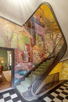 the staircase is painted with colorful images and paintings on it's walls, along with black and white checkered flooring