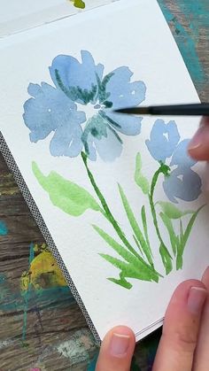 someone is painting flowers with watercolors on paper