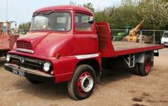 an old red truck is parked in the dirt