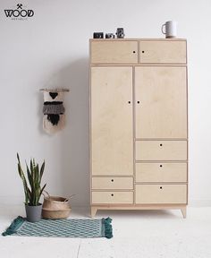 a wooden cabinet sitting next to a potted plant on top of a white floor