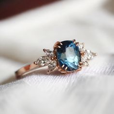 an engagement ring with a blue topaz surrounded by three white diamonds on a piece of cloth