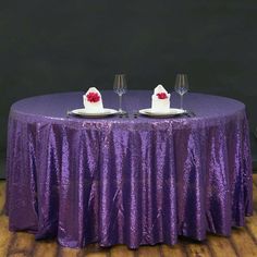 two wine glasses sitting on top of a purple table cloth