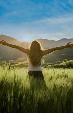 a woman standing in a field with her arms outstretched