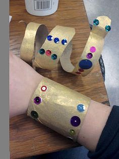 a person is wearing gold paper with colorful jewels on it's arms and wrist