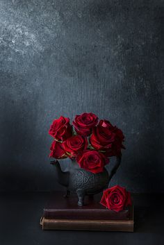 a vase filled with red roses sitting on top of a book