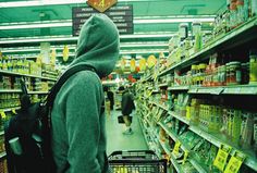 a person in a hooded sweatshirt is walking through a grocery store aisle