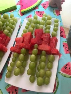 watermelon and grapes are arranged on white plates