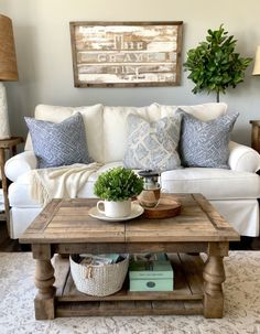 a living room with a white couch and wooden coffee table in front of a painting on the wall