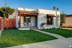 a small white house with green grass and palm trees