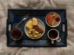 a tray with breakfast foods on it and two cups of coffee next to each other