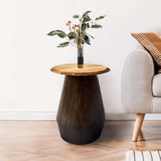 a vase with flowers sitting on top of a wooden table next to a couch in a living room