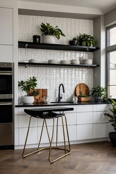 a kitchen with white cabinets and black counter tops, plants on the shelf above the sink