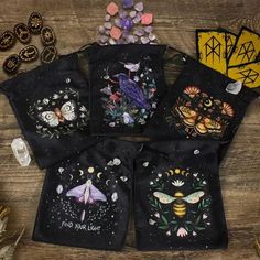 five bags with embroidered designs on them sitting on a wooden table next to other items