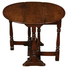 an old wooden table with two legs and a small round wood table top on one end