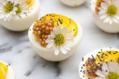 an assortment of deviled eggs decorated with flowers and sprinkles on a marble surface