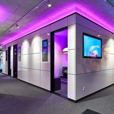 an empty room with purple lighting and a flat screen tv on the wall in front of it