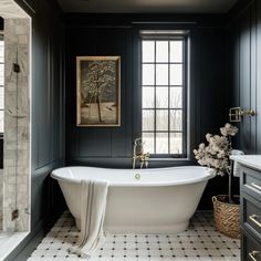 a white bath tub sitting next to a window in a black and white tiled bathroom