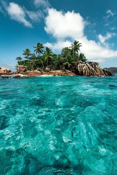 an island in the ocean with palm trees on it's sides and clear blue water