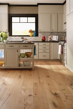 a kitchen with white cabinets and wood floors is pictured in this image, there are bowls on the island