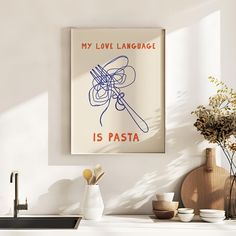 a poster hanging on the wall above a sink in a white kitchen with wooden utensils