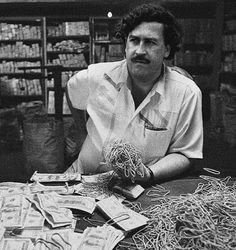 a man sitting at a table in front of stacks of money and piles of noodles