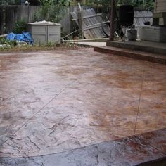 a concrete patio with steps leading up to the back door and an outdoor kitchen in the background