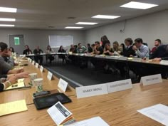 a group of people sitting at long tables with papers on the table in front of them