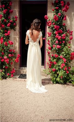 a woman in a white dress is standing outside