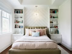 a bed sitting in a bedroom next to a window with bookshelves behind it