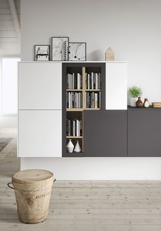 a white and black bookcase with books on it next to a wooden trash can