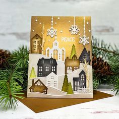 a christmas card with an image of houses and snowflakes hanging from the tree