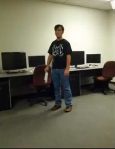 a man standing in an office holding a wii controller