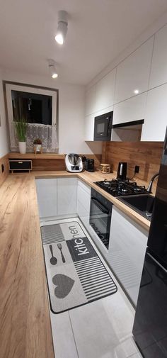 a kitchen with wooden floors and white cabinets, black appliances and wood flooring on the walls